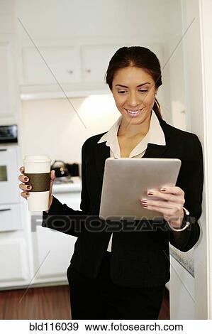 Stock Photo - Mixed race businesswoman using tablet computer in kitchen. Fotosearch