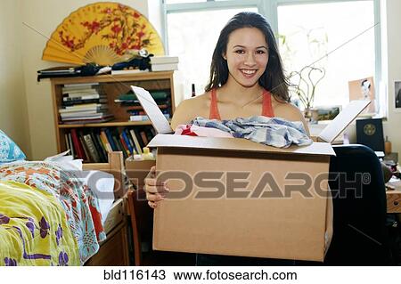Stock Image - Mixed race college student unpacking in dorm. Fotosearch