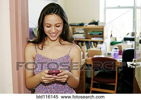 Mixed race college student using cell phone in dorm View Large Photo Image Stock Photography - Mixed race college student using cell phone in dorm. Fotosearch