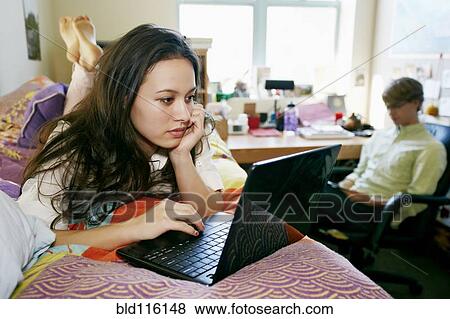 Stock Photo - Mixed race college student using laptop in dorm. Fotosearch