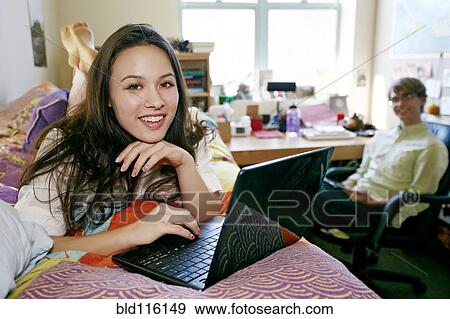 Mixed race college student using laptop in dorm View Large Photo Image Stock Photo - Mixed race college student using laptop in dorm. Fotosearch