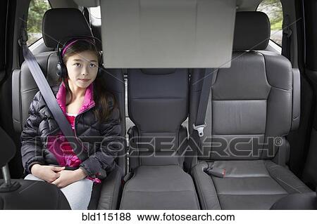 Stock Photo - Mixed race girl watching television in backseat. Fotosearch