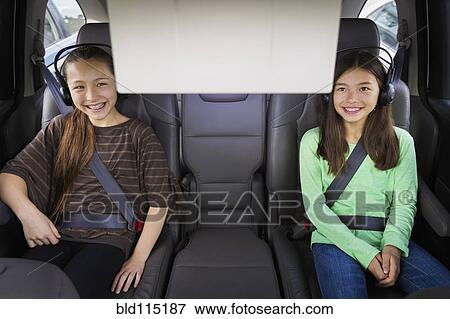 Stock Photo - Mixed race girls watching television in backseat. Fotosearch