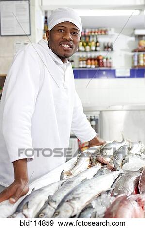 Mixed race grocer preparing fish in market View Large Photo Image Stock Photo - Mixed race grocer preparing fish in market. Fotosearch