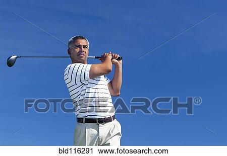 Stock Image - Mixed race man playing golf outdoors. Fotosearch