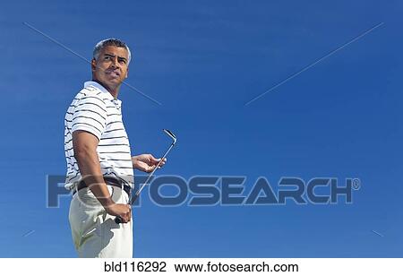 Stock Image - Mixed race man playing golf outdoors. Fotosearch