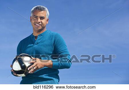 Stock Photograph - Mixed race man playing soccer outdoors. Fotosearch