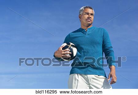 Stock Photography - Mixed race man playing soccer outdoors. Fotosearch