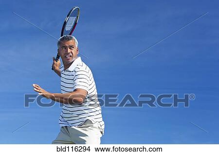 Picture - Mixed race man playing tennis outdoors. Fotosearch