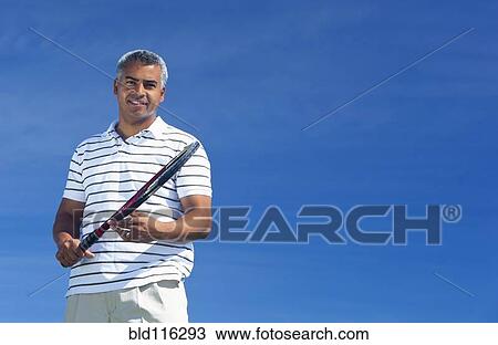 Stock Image - Mixed race man playing tennis outdoors. Fotosearch