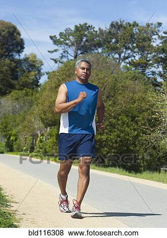 Stock Photo - Mixed race man running on rural road. Fotosearch