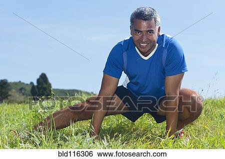 Stock Photograph - Mixed race man stretching outdoors. Fotosearch