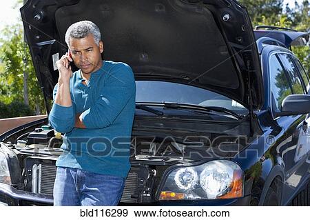 Stock Photo - Mixed race man with broken down car. Fotosearch