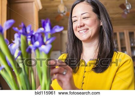 Stock Image - Mixed race woman arranging flowers. Fotosearch