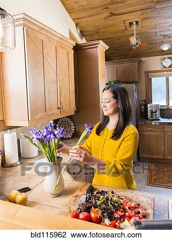 Stock Image - Mixed race woman arranging flowers. Fotosearch