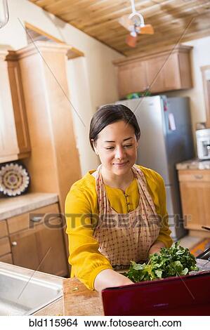 Picture - Mixed race woman cooking in kitchen. Fotosearch