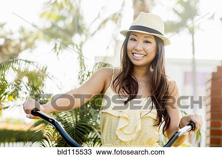 Stock Image - Mixed race woman riding bicycle. Fotosearch