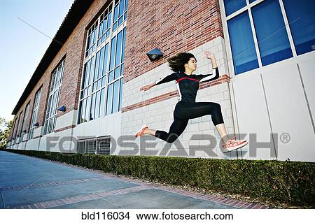 Picture - Mixed race woman running on city street. Fotosearch