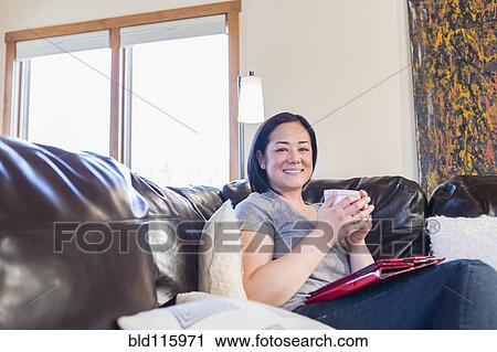 Mixed race woman using digital tablet on sofa View Large Photo Image Stock Image - Mixed race woman using digital tablet on sofa. Fotosearch