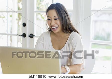 Stock Image - Mixed race woman using laptop. Fotosearch