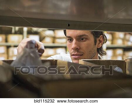 Mixed race worker examining bin in textile factory View Large Photo Image Stock Image - Mixed race worker examining bin in textile factory. Fotosearch