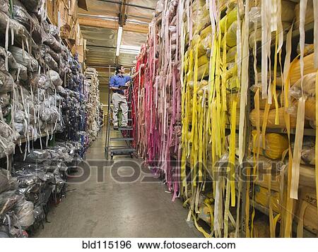 Stock Photograph - Mixed race worker examining fabric in textile factory. Fotosearch