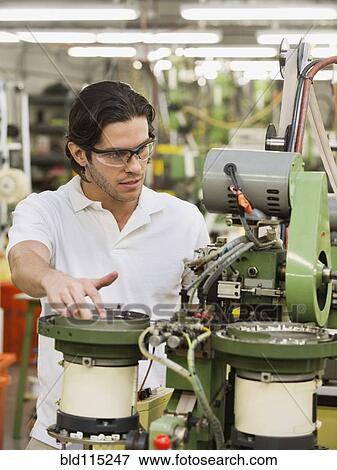 Stock Photo - Mixed race worker operating machinery in textile factory. Fotosearch