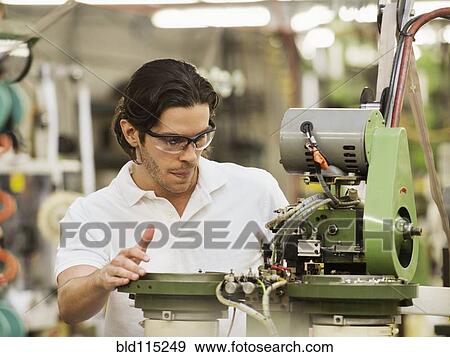 Stock Photo - Mixed race worker operating machinery in textile factory. Fotosearch