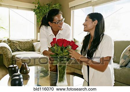 Stock Image - Mother and daughter arranging flowers in vase. Fotosearch