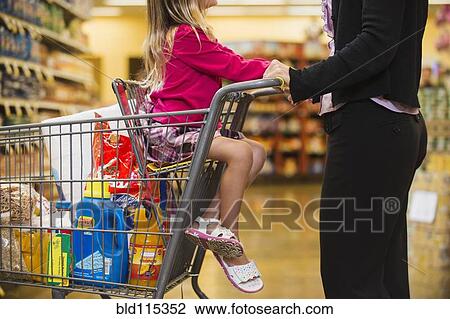 Stock Image - Mother and daughter shopping in grocery store. Fotosearch
