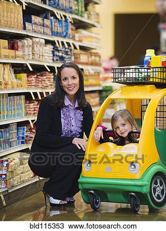 Stock Image - Mother and daughter shopping in grocery store. Fotosearch