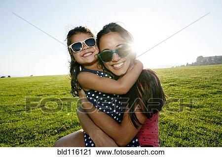 Stock Image - Mother and daughter smiling in field. Fotosearch