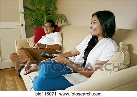 Stock Image - Mother and daughter watching television together. Fotosearch