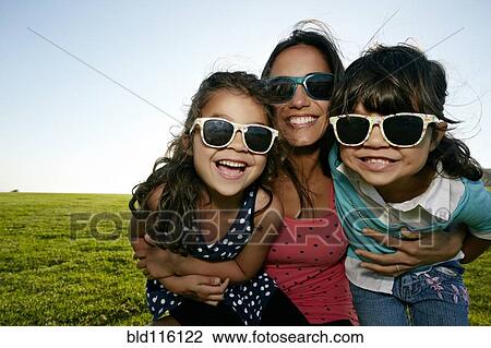 Stock Image - Mother and daughters smiling in field. Fotosearch