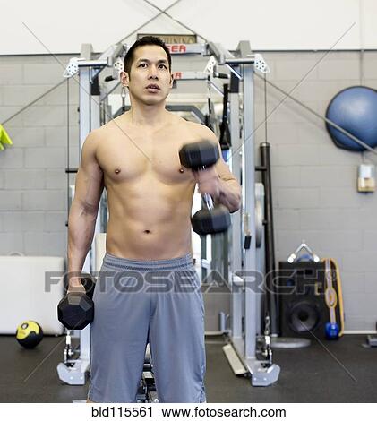 Stock Image - Pacific Islander man lifting weights in gym. Fotosearch