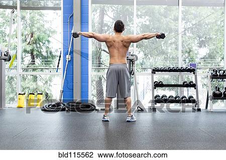 Stock Image - Pacific Islander man lifting weights in gym. Fotosearch