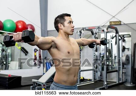 Stock Image - Pacific Islander man lifting weights in gym. Fotosearch