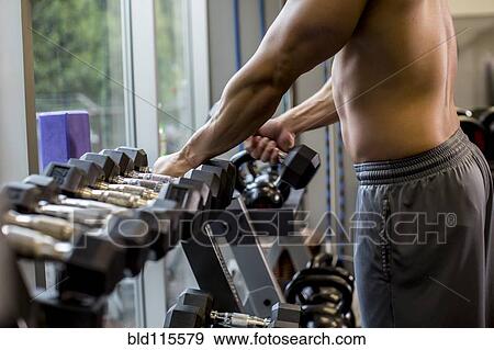 Stock Photo - Pacific Islander man lifting weights in gym. Fotosearch