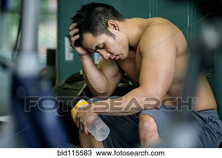 Stock Image - Pacific Islander man resting in gym. Fotosearch