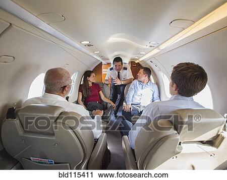 Pilot talking to business people on airplane View Large Photo Image Stock Image - Pilot talking to business people on airplane. Fotosearch