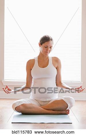 Stock Image - Pregnant woman meditating on yoga mat. Fotosearch