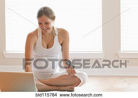 Picture - Pregnant woman shopping online. Fotosearch