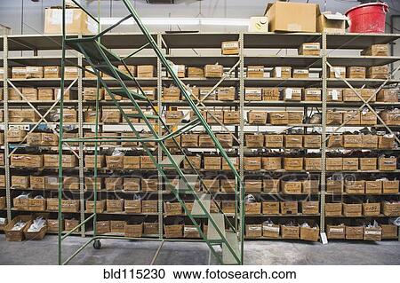 Stock Image - Rolling stairs by shelves in textile factory. Fotosearch