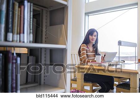 Picture - Student working at desk in library. Fotosearch