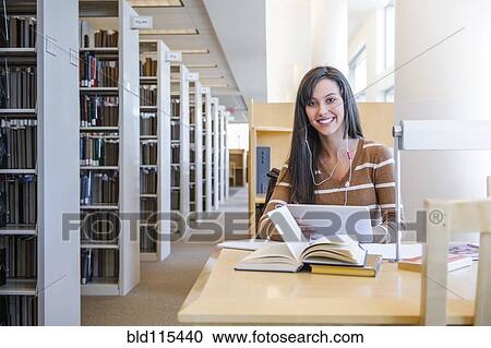 Stock Image - Student working at desk in library. Fotosearch