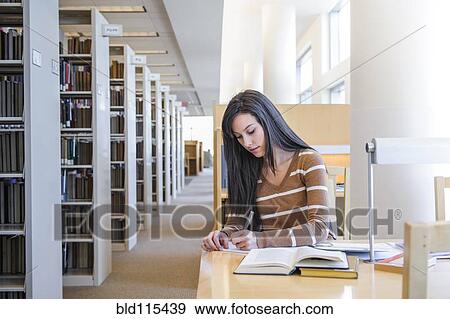 Stock Photo - Student working at desk in library. Fotosearch