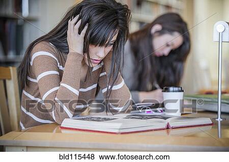 Stock Photo - Student working at desk in library. Fotosearch