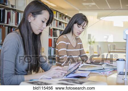 Stock Photograph - Students working at desk in library. Fotosearch