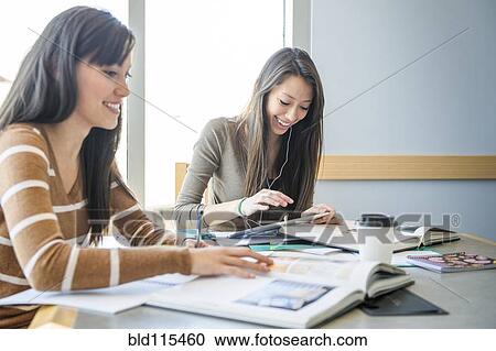 Stock Image - Students working together at desk. Fotosearch
