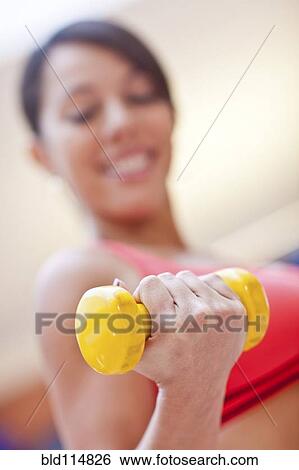 Stock Photograph - Woman lifting weights in gym. Fotosearch